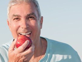 A smiling man enjoying an apple